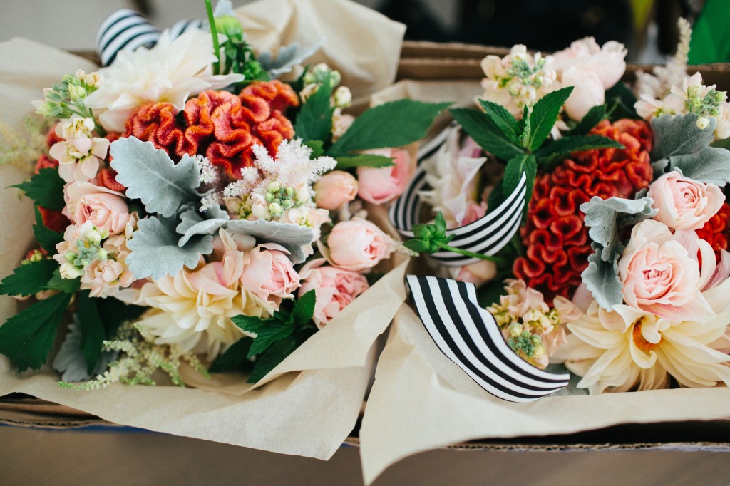 Bridesmaids' bouquets in peach, coral, grey with black and white striped ribbon. Dahlias, coxcomb, dusty miller, astilbe, and spray garden roses.