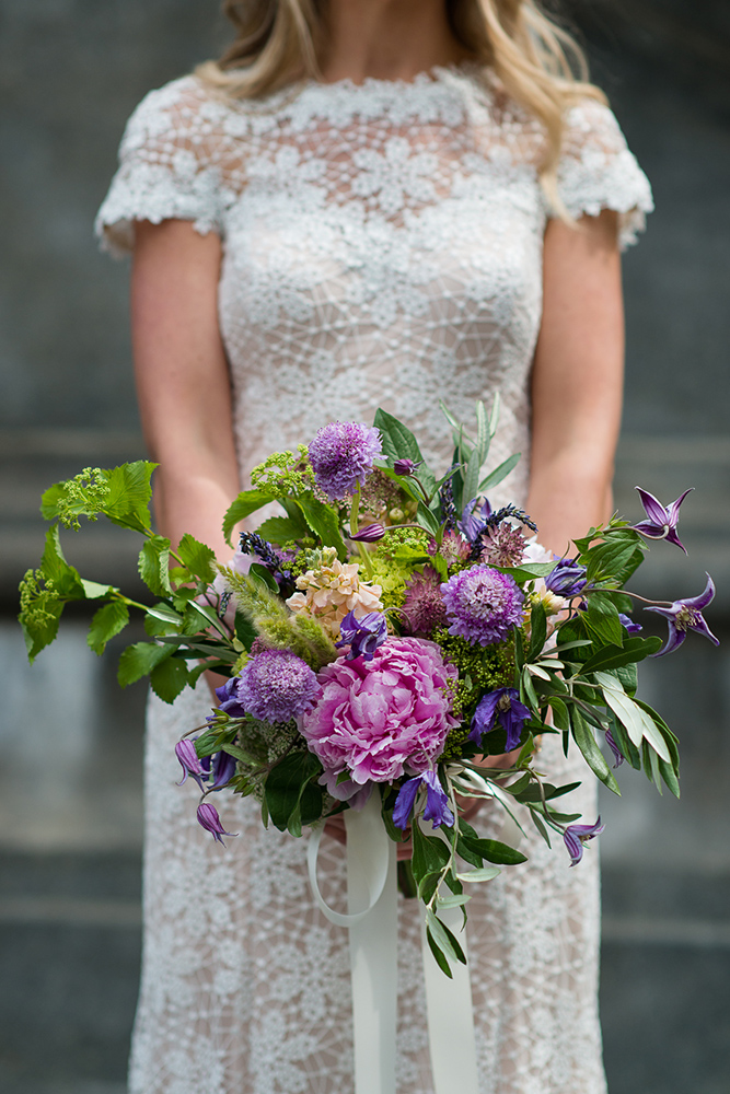 Garden style wedding bouquet in pink and purple with peonies, viburnum, scabiosa, olive, and clematis.