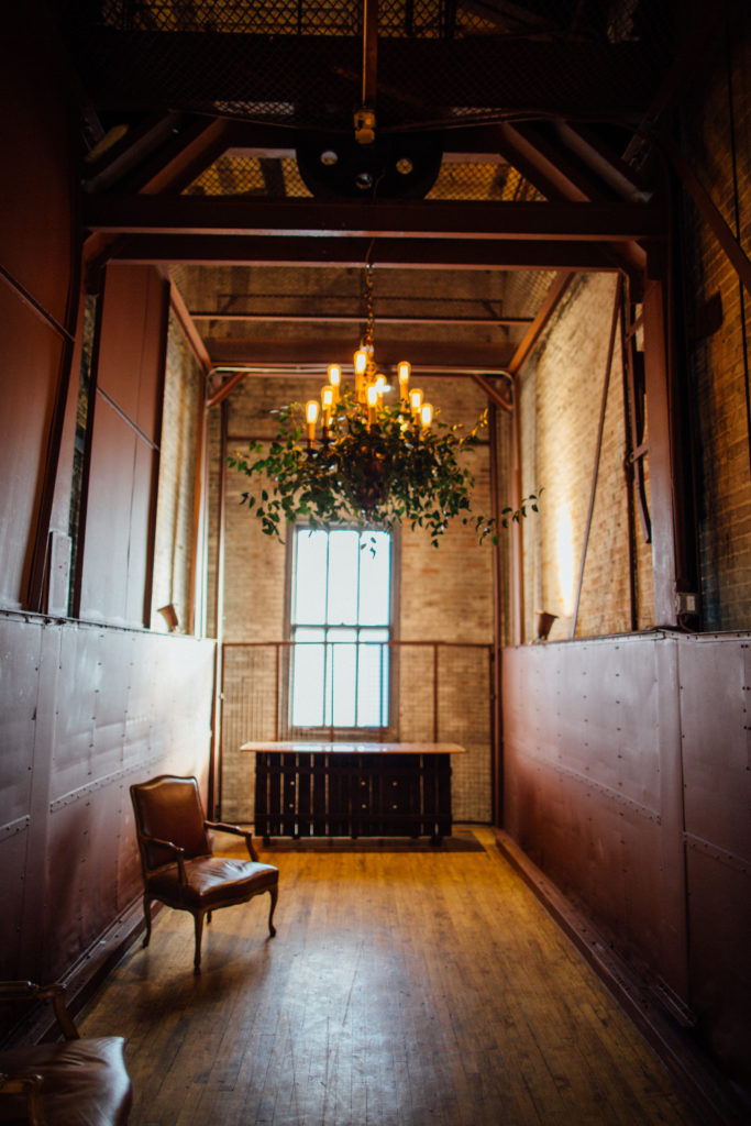 Bridgeport Art Center in Chicago elevator with chandelier and foliage for wedding reception. 