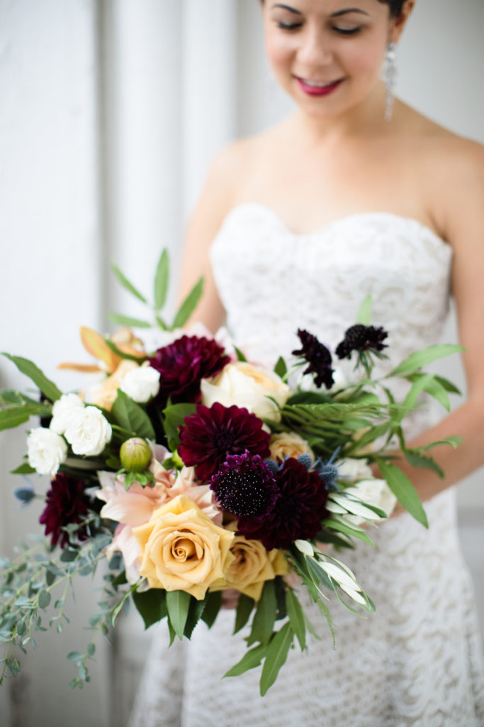 Plum scabiosas, garden roses, thistle, and burgundy dahlias bridal bouquet for a caramel and burgundy fall wedding.
