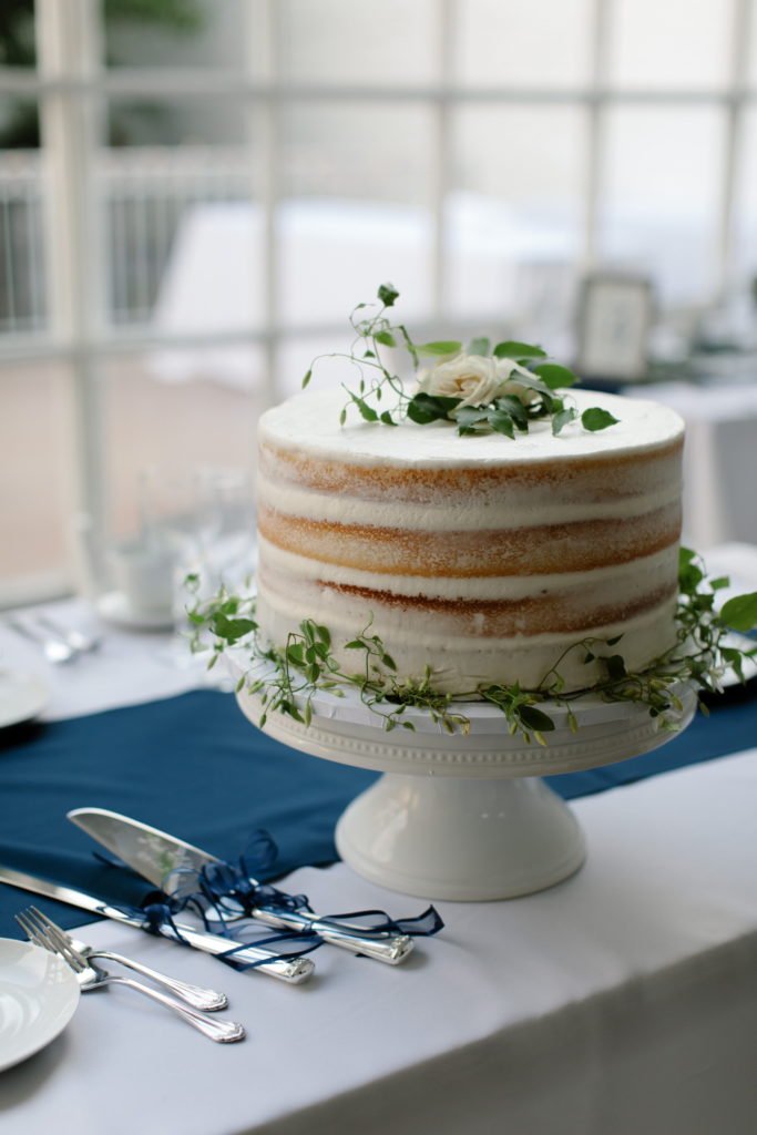 Naked frosting cake in vanilla with clematis vines on cake stand for a sage and white summer wedding at Prairie Production in Chicago.