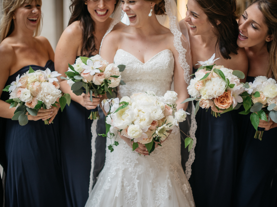 Navy and white bridal party with bouquets of white autumn clematis with vines, blush and white garden roses and peonies, and eucalyptus. 