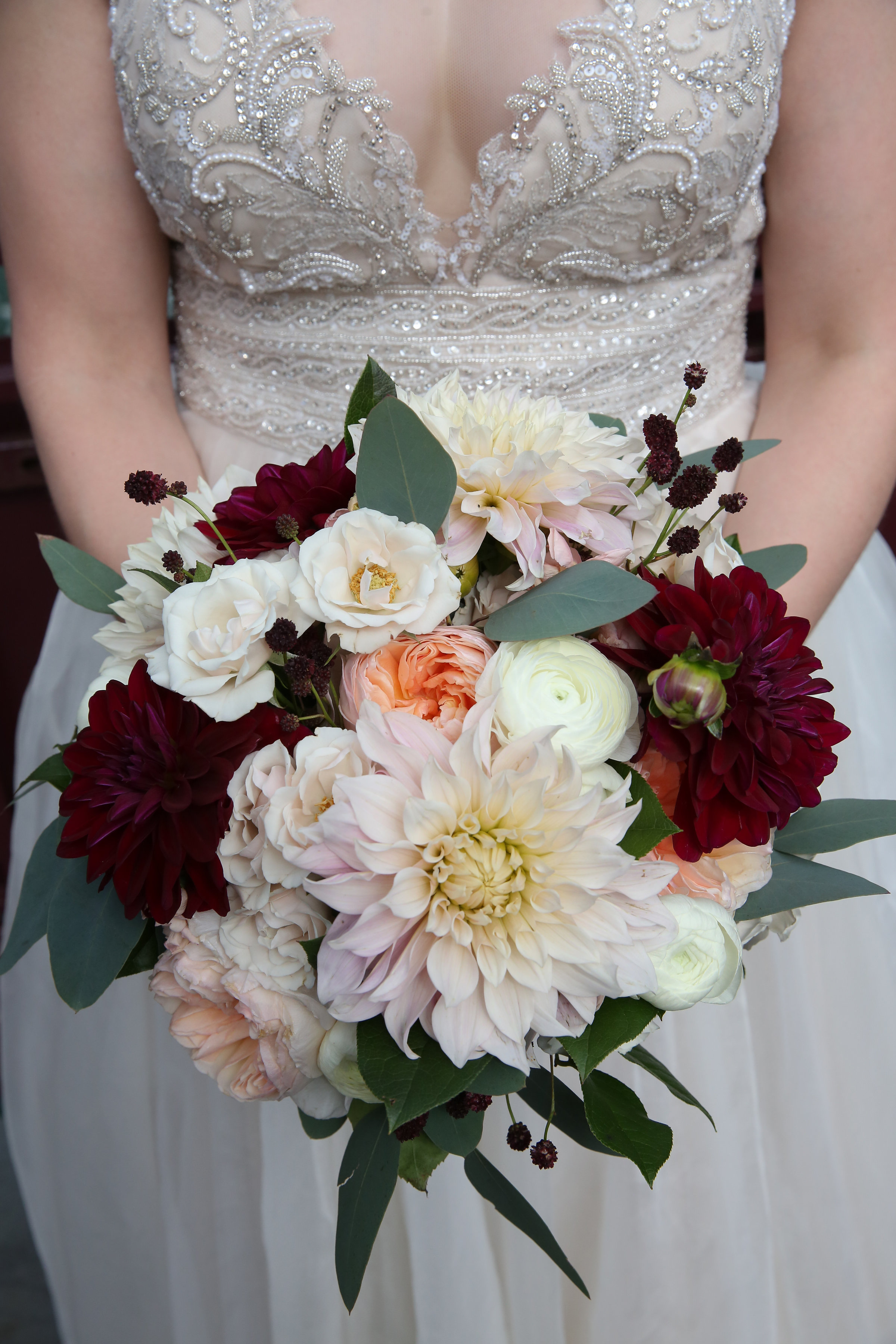 Bridal bouquet with spring flowers of burgundy and blush dahlias, garden roses, and white majolica.