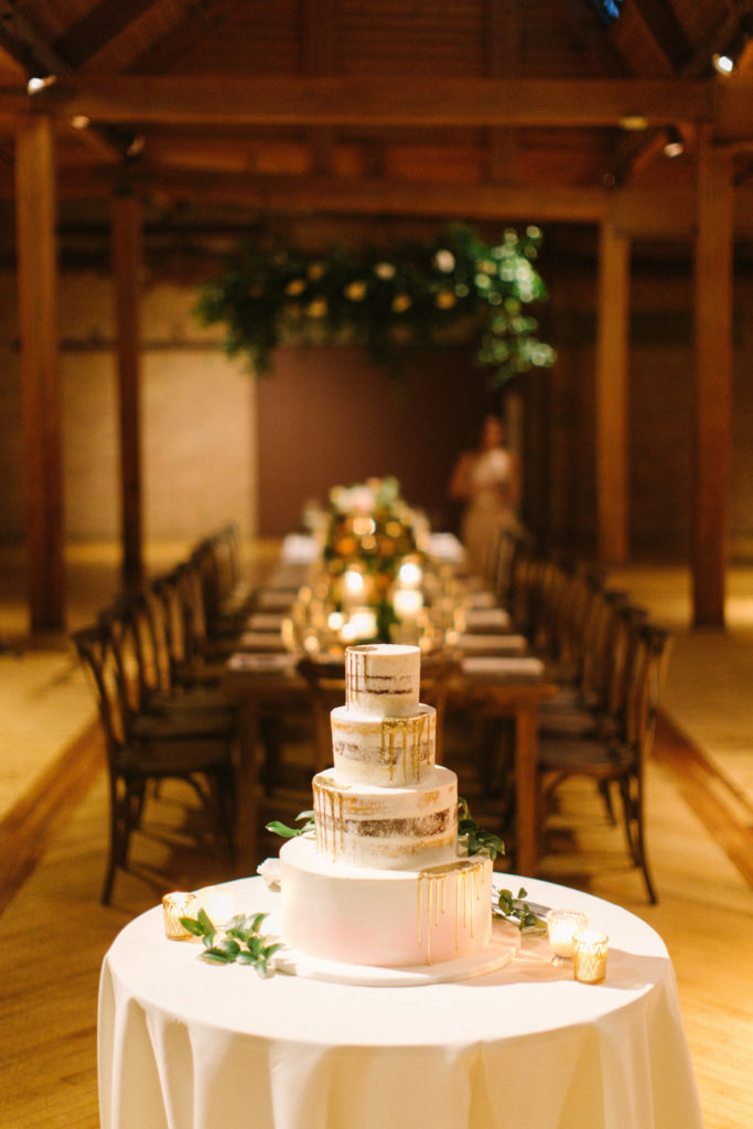 Bridgeport Art Center's Skyline Loft in Chicago wedding reception with rustic tables, floating floral installation, and golden and ivory cake.