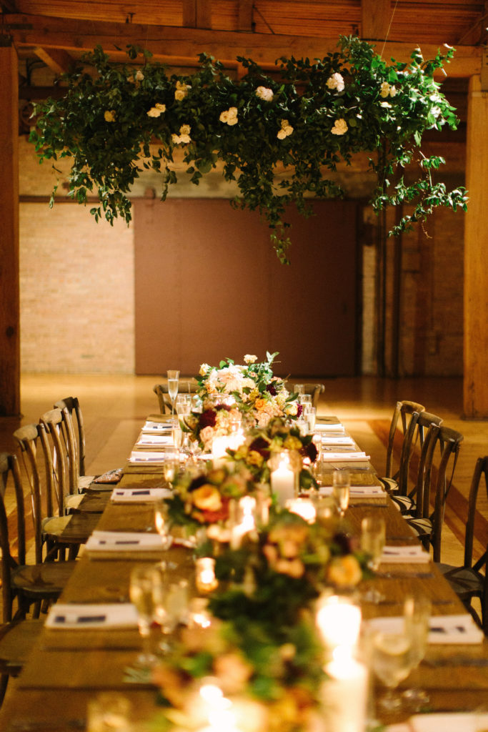 Bridgeport Art Center's Skyline Loft in Chicago wedding reception with hanging floral installation over head table burgundy and ivory flowers.