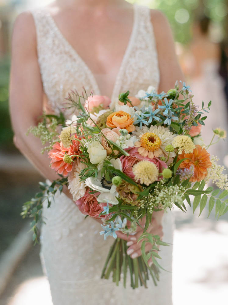 Bride with romantic vintage-inspired zinnia, ranunculus, roses, and jasmine bouquet.