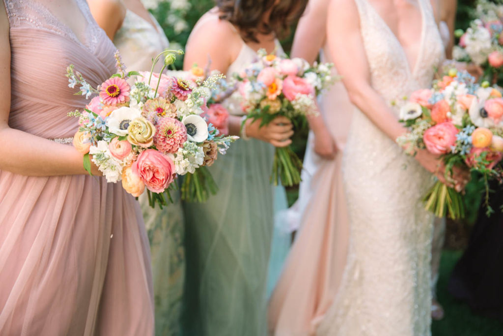 Colorful, mixed pastel blooms of zinnias, anemones, garden roses, tweedia, and ranunculus for the wedding party's wildflowery bouquets for a summer wedding at Salvage One.