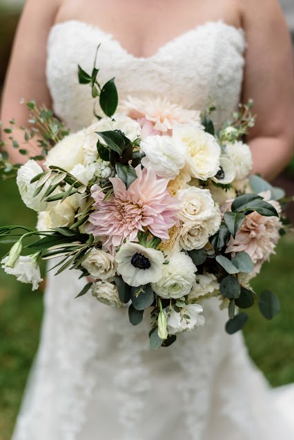 Lush bridal bouquet of pink dahlias, white ranunculus, anemone, lisianthus, and majolica roses for a late summer wedding.