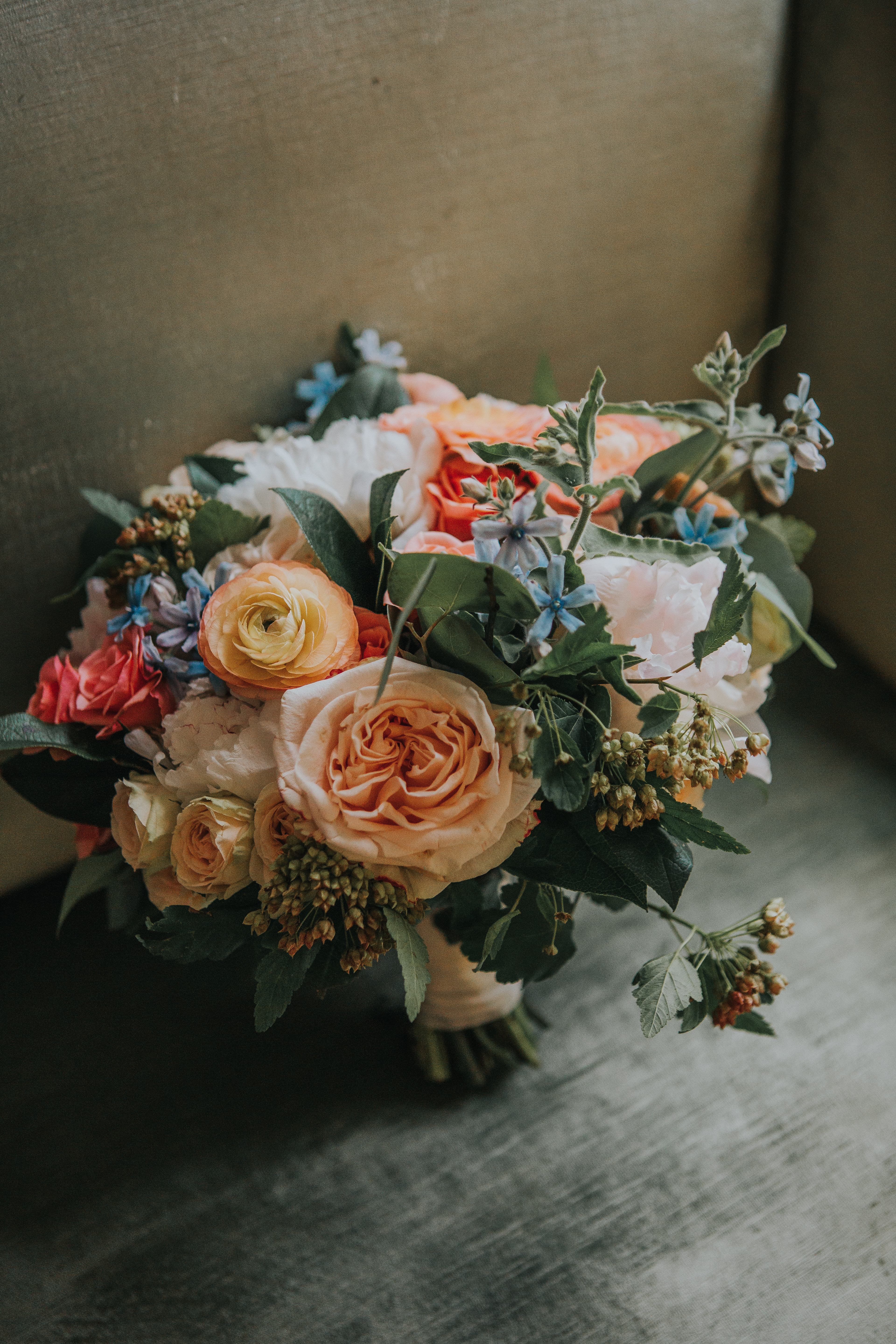 Bridal bouquet vintage style with orange ranunculus, peach garden roses, and tweedia.