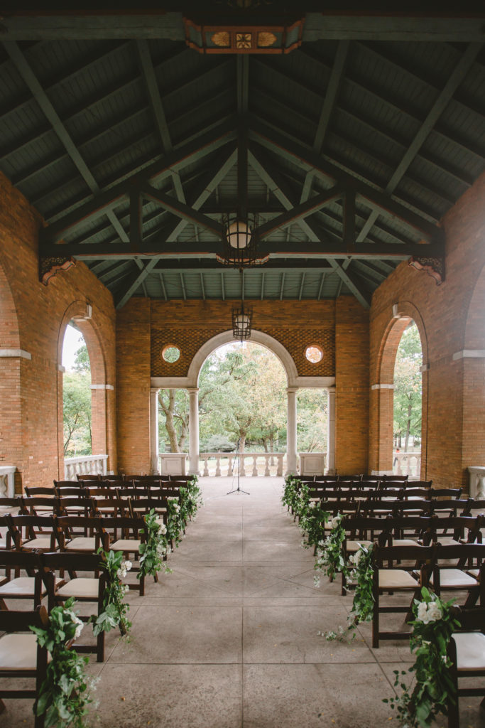 Late summer outdoor wedding in Chicago at Columbus Park Refectory  with foliage and ivory rose lined aisle at the ceremony.