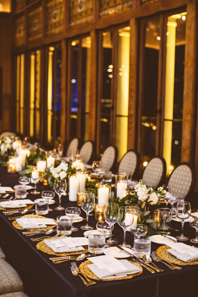 Black, gold, and ivory wedding palette at the Chicago Athletic Association, with head table decorated with pillar candles, eucalyptus, and white bouquets for a timeless look.
