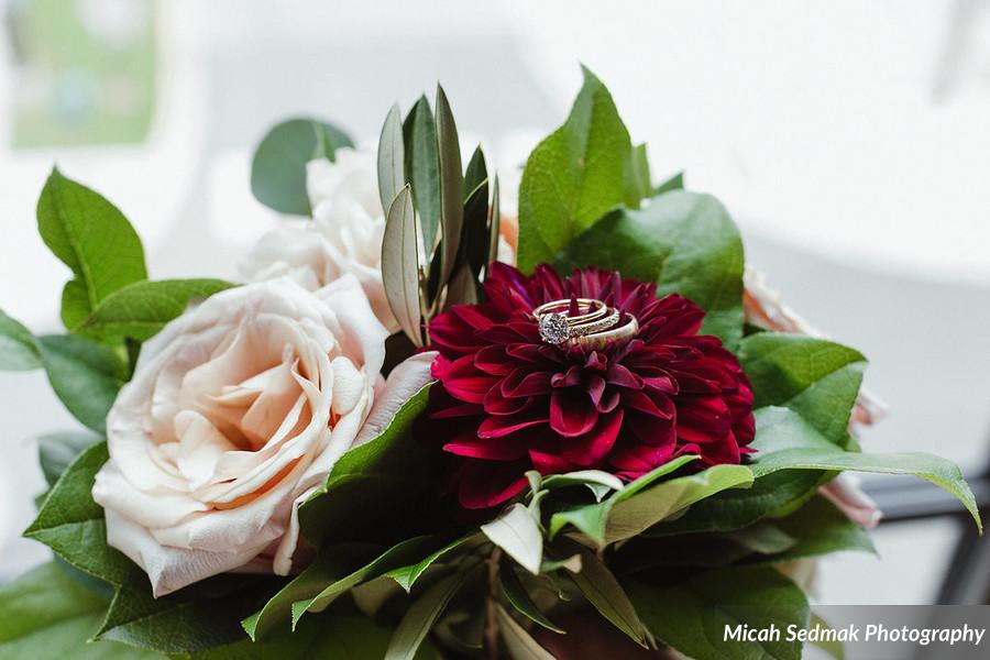Wedding flower portrait with rings, wine dahlia, and blush garden rose.