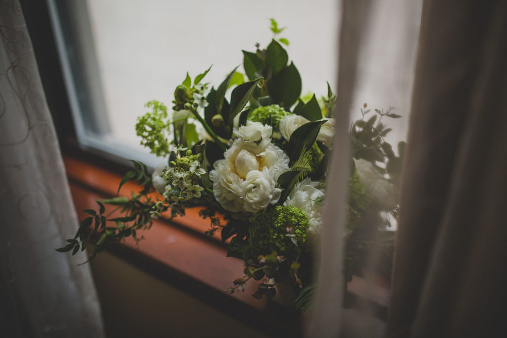 Bridal bouquet of peonies, ranunculus, snowball viburnum, fern, ivory coast lily for winter wedding.