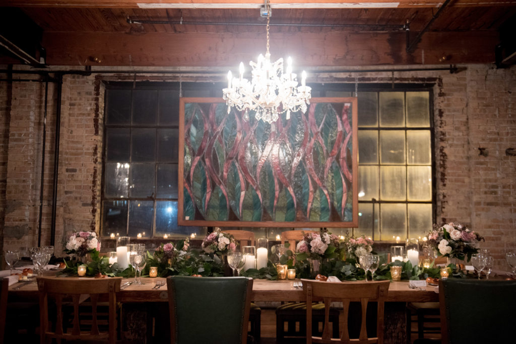 Head table with bouquets, garland, and candles at a romantic winter wedding reception at Salvage One.