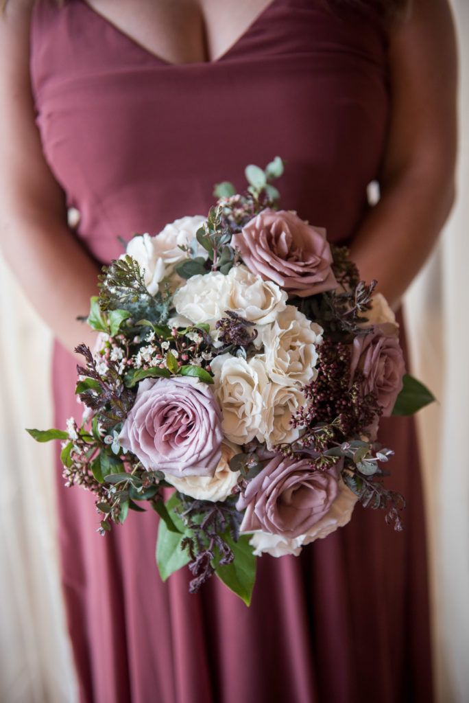 Bridesmaid's bouquet for winter wedding, featuring dusty purple roses, white majolika, and eucalyptus. Jenny Yoo bridesmaid dress in cinnamon rose.
