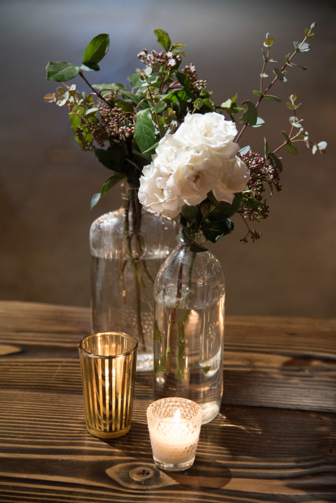 Vintage glass bottle arrangements of seedum and white majolica at winter wedding at Salvage One.