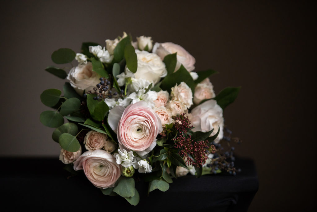 Winter bridal bouquet with blush ranunculus, berries, and silver dollar eucalyptus.