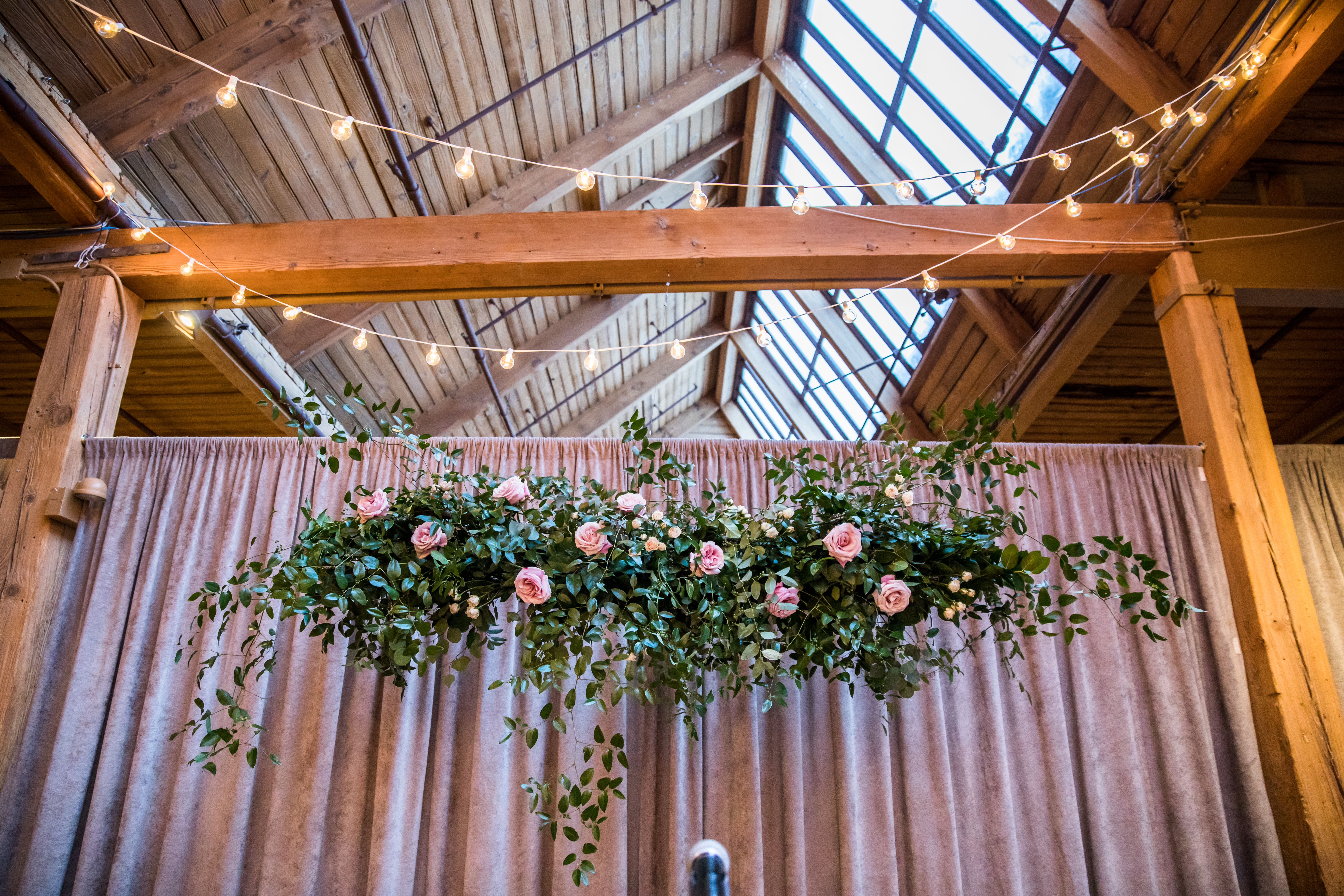 Bridgeport Art Center Skyline Loft for winter wedding with string lights and floating altar piece of pink garden roses and foliage on mauve background..