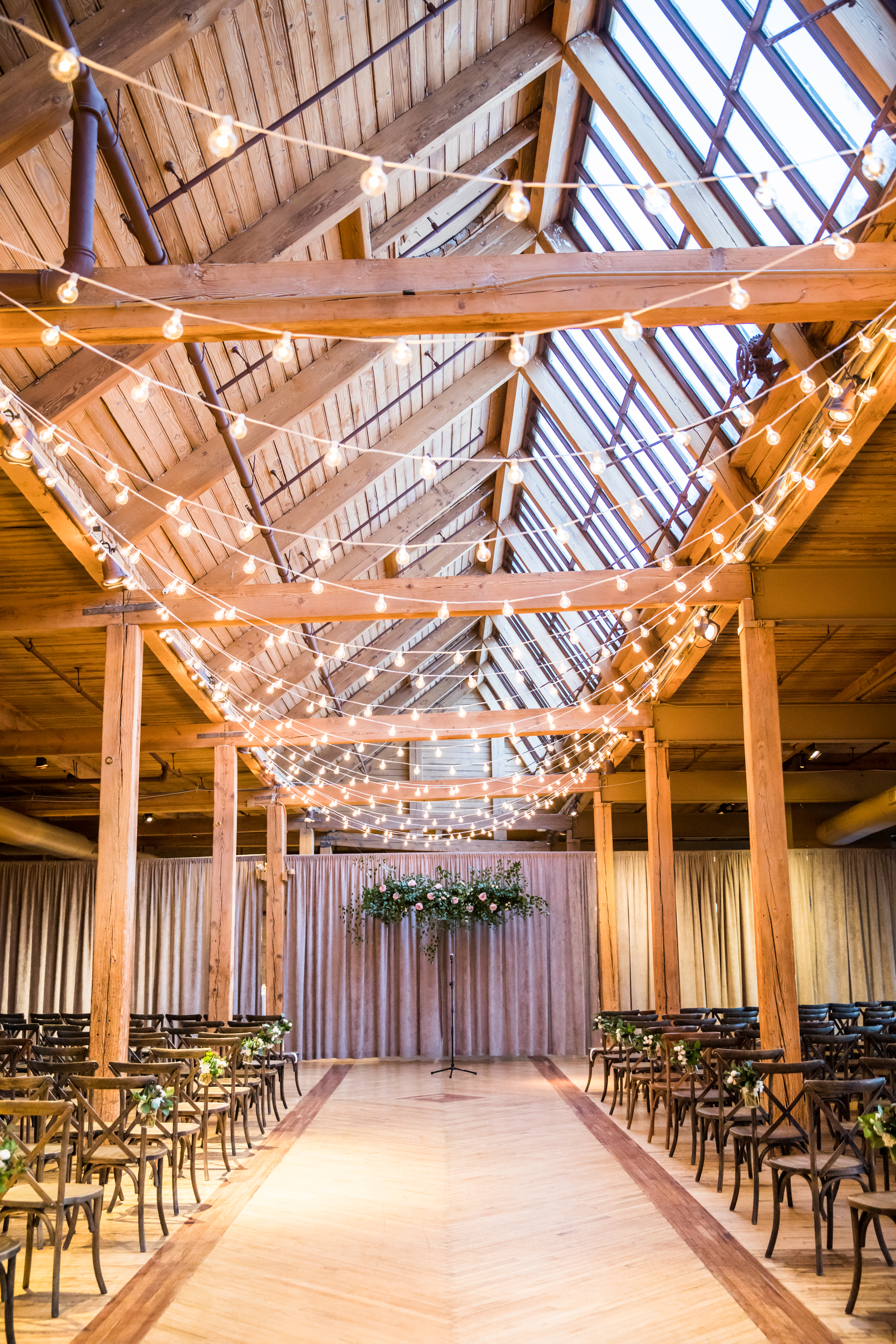 Bridgeport Art Center Skyline Loft for winter wedding with string lights and suspended ceremony installation of pink garden roses and foliage on mauve background..