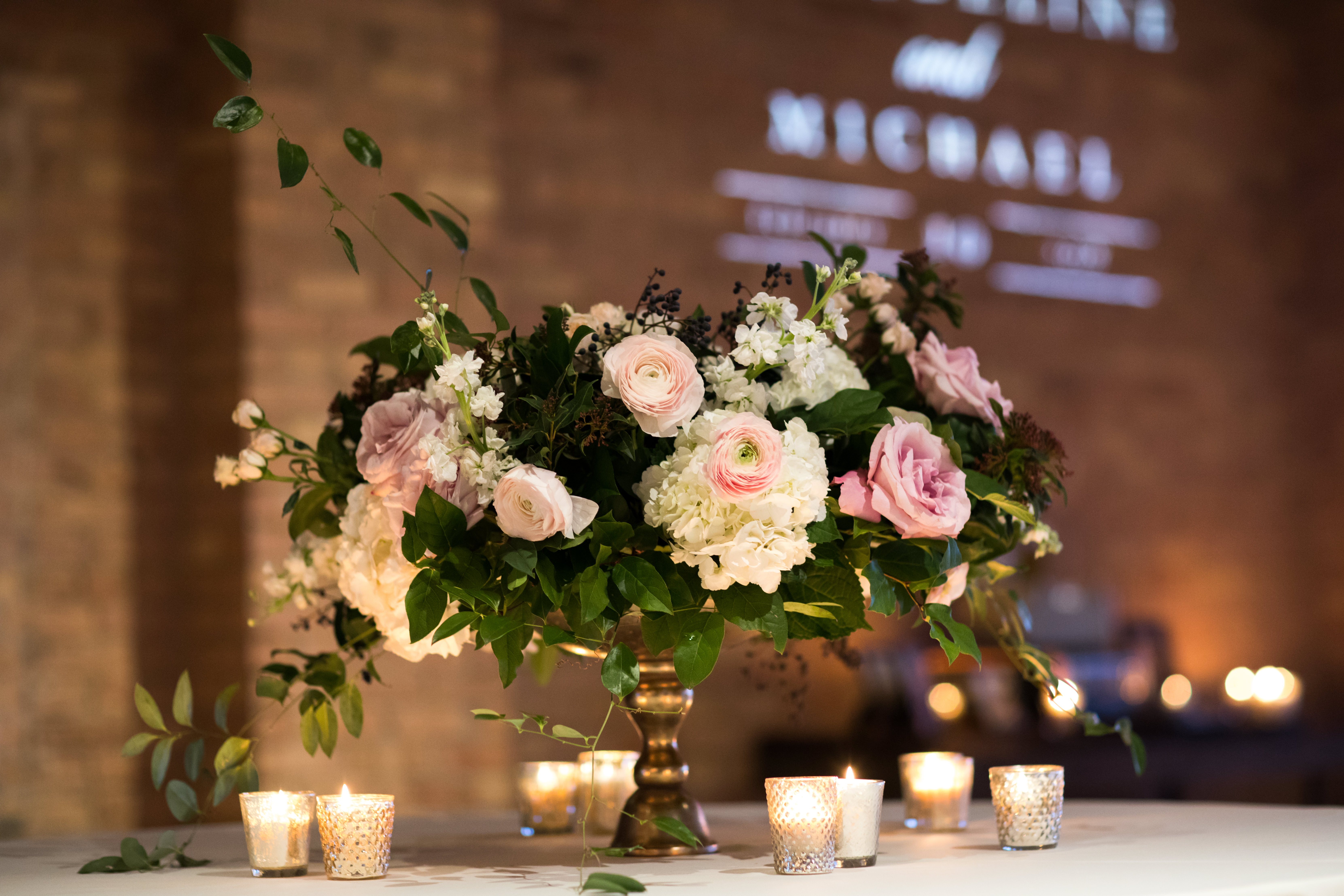 Winter wedding arrangement of white hydrangea, pink garden roses, and blush ranunculus for the escort card table.