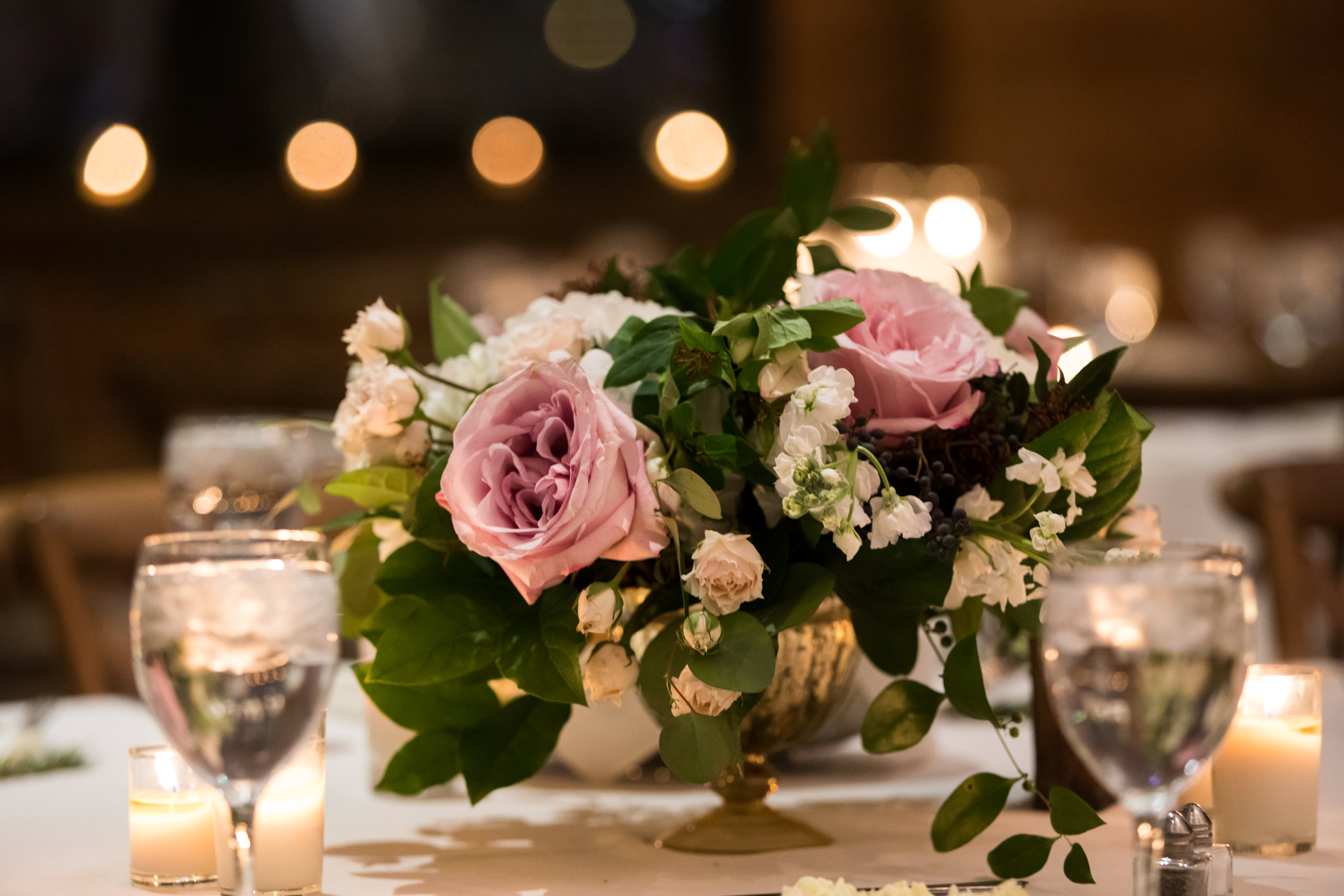 Winter wedding floral arrangment with garden roses, blush spray roses, and white hydrangea in gold vase.
