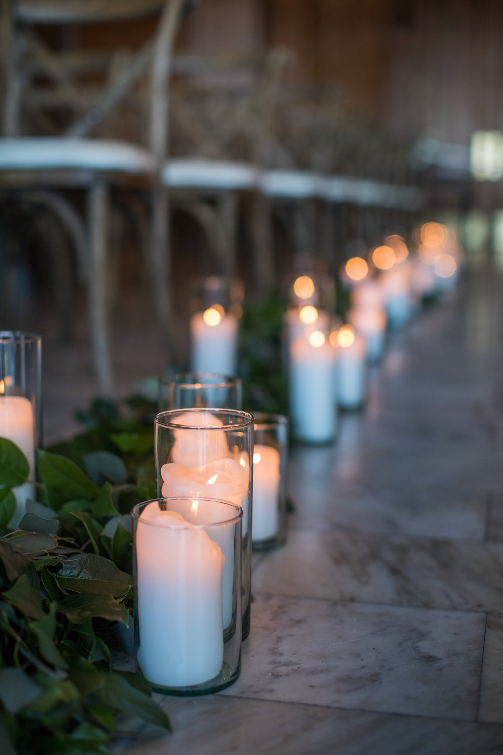 Wedding ceremony aisle with garlands and candles.