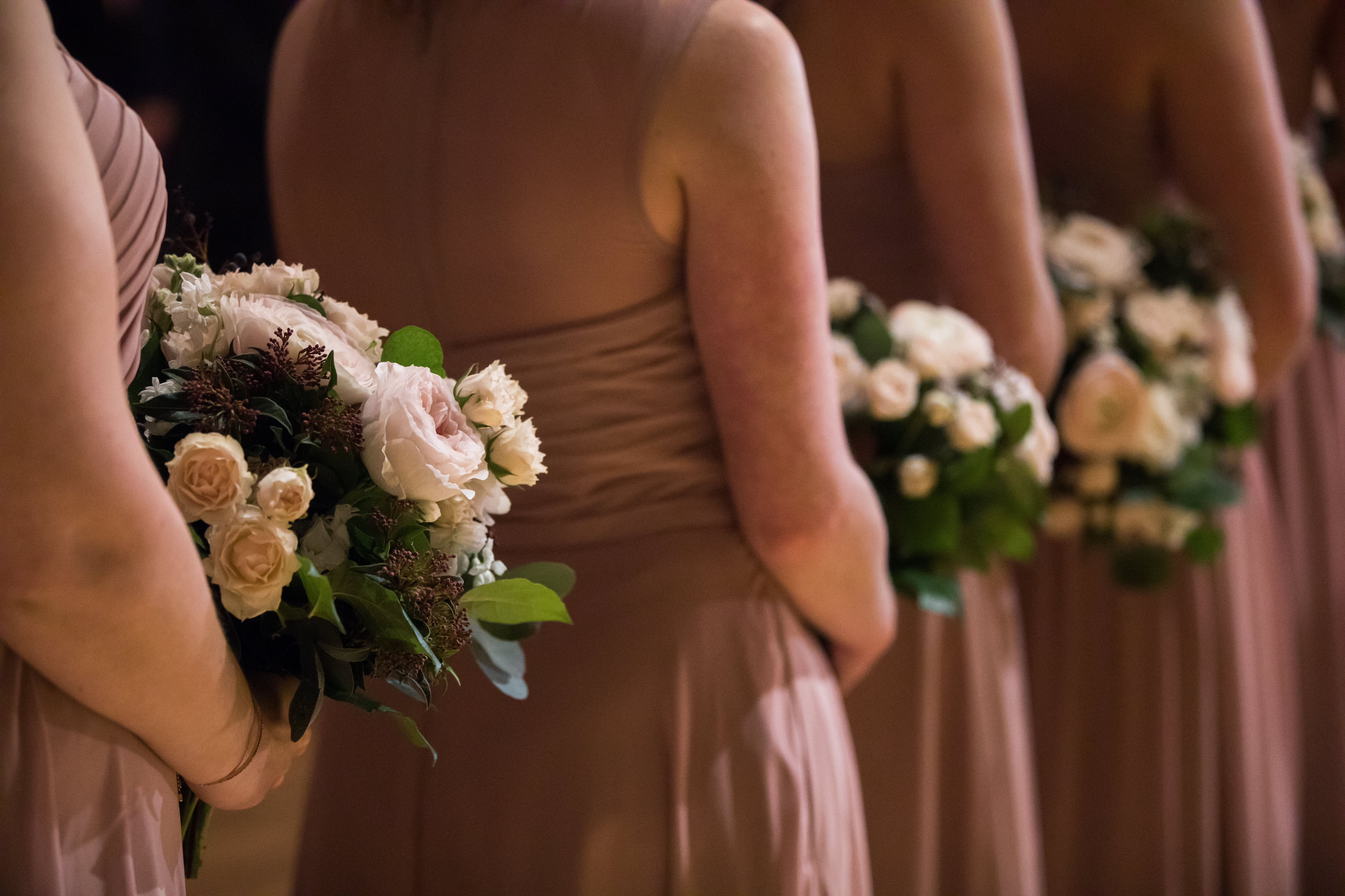 Dusty rose bridesmaids' dresses with bouquets at winter wedding ceremony at Bridgeport Art Center Skyline Loft in Chicago