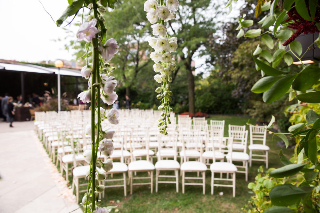 Outdoor fall wedding with hanging flowers of ivory and lilac delphinium.