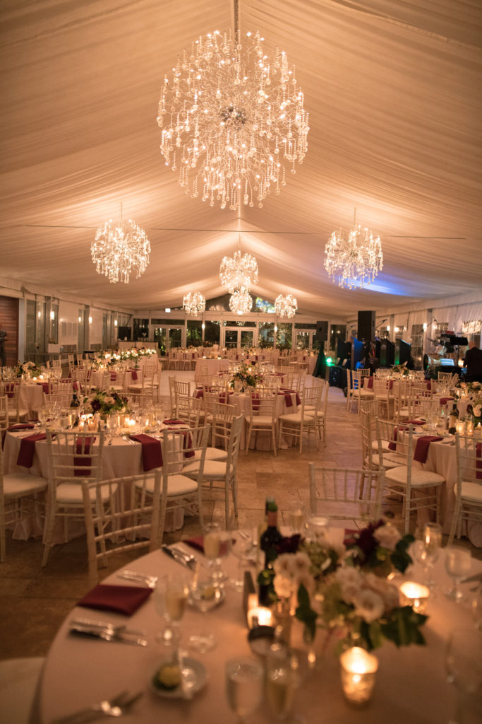 Romantic tent wedding reception in Chicago with small centerpieces of majolica roses in ivory and garden roses in blush.