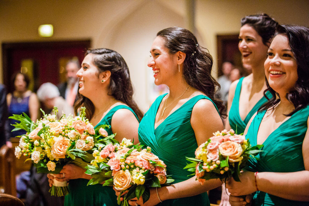 Spring wedding bridesmaids at Church of Saint Bride with bouquets in peach and pink with ranunculus, garden roses, and hypericum berries.