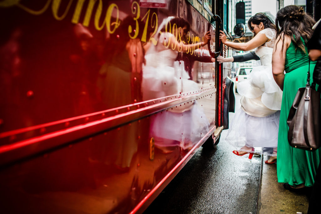 Spring bride steps onto red trolley for reception.