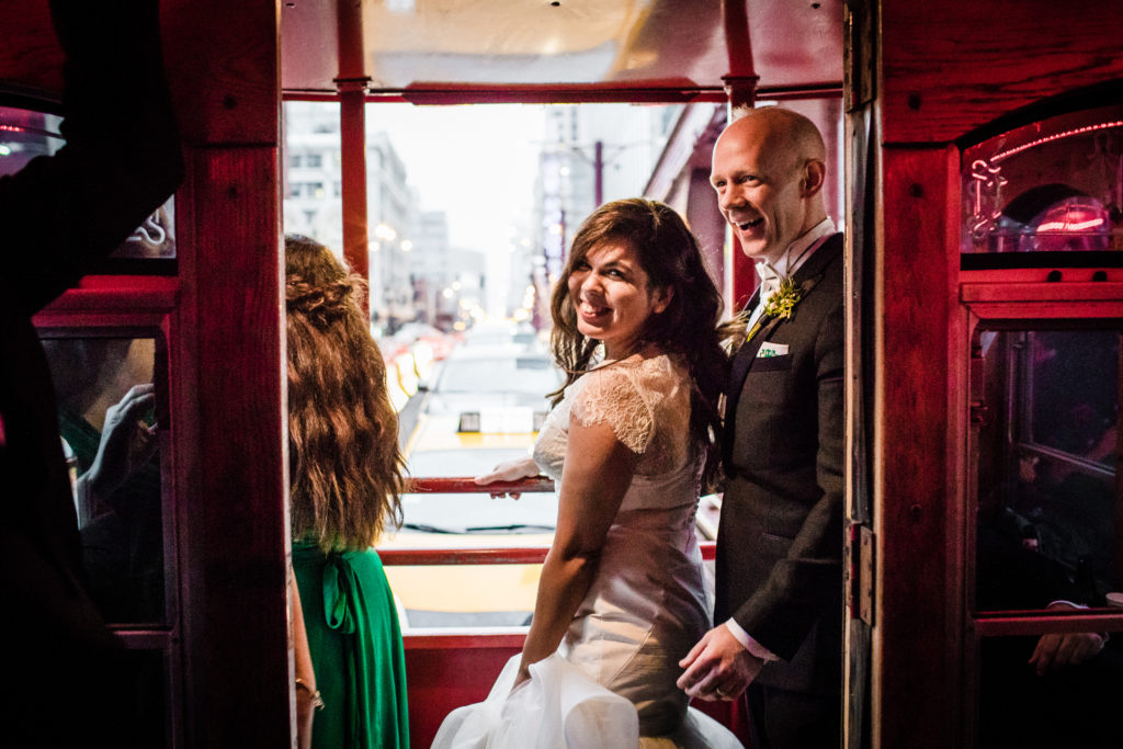 Spring bride and groom on red trolley; groom's boutonniere of rosemary and hypericum berries.