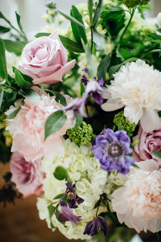 Flower close-up for spring wedding: pale pink peonies and garden roses, purple scabiosa and clematis, white hydrangea, and snowball viburnum.