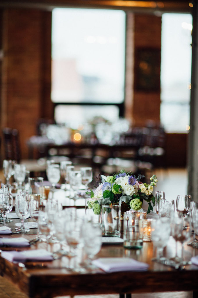 Spring wedding reception table setting with gardeny arrangements in purple, pale green, and ivory at City View Loft in Chicago.