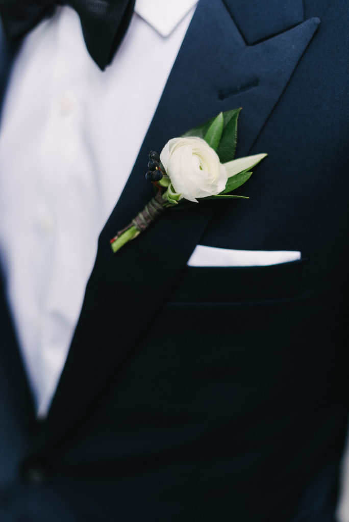 Simple and classic boutonniere of white ranunculus and eucalyptus.
