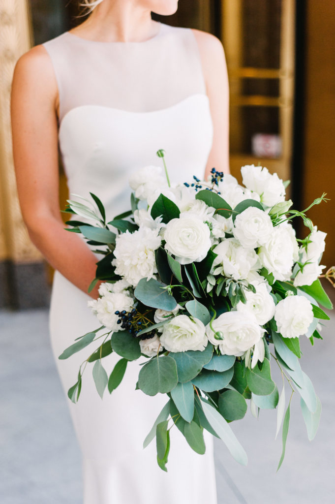 Lush bridal bouquet in white and sage green with peonies, ranunculus, lisianthus, berries, and eucalpytus.