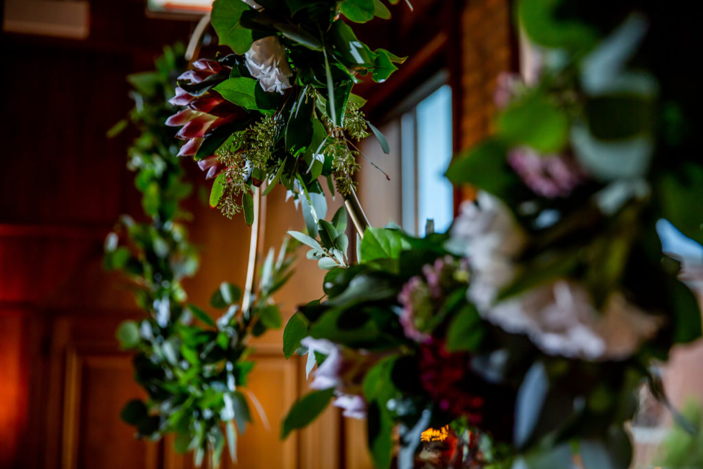 Hanging ceremonial wreaths made of protea, dahlias, garden roses, and white majolika for a fall wedding at Revolution Brewing. 
