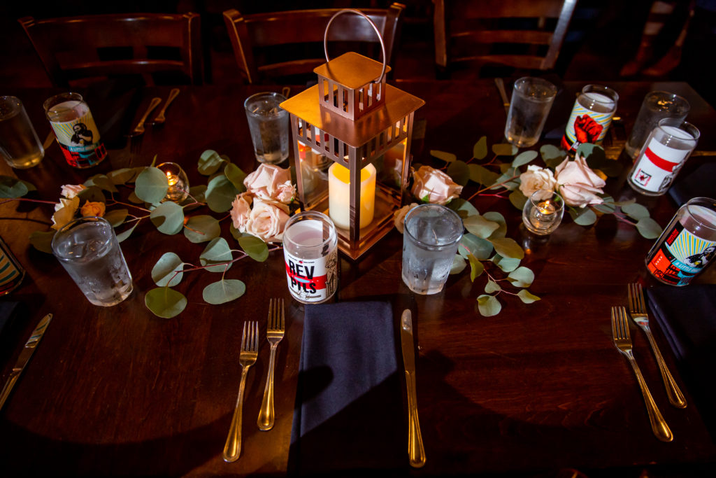 Reception tablescape with eucalyptus, bronze lantern, blush garden roses, and local beer at Revolution Brewing for a fall wedding. 
