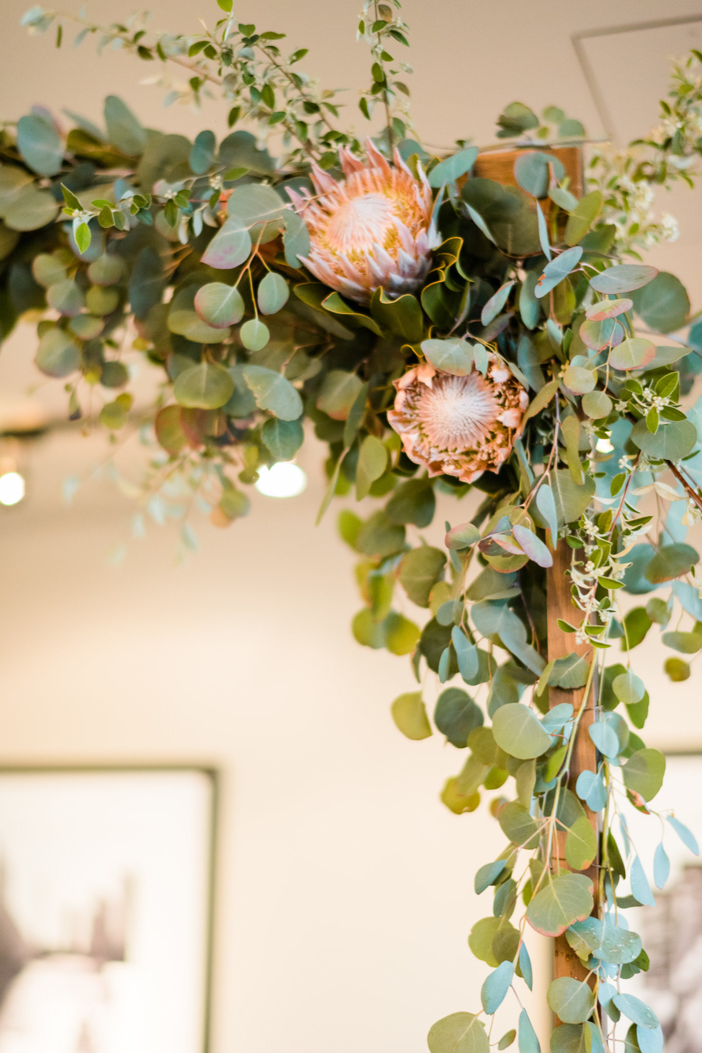 Eucalyptus, protea, and flowering branches on ceremonial arch for spring wedding at River Roast Chicago.