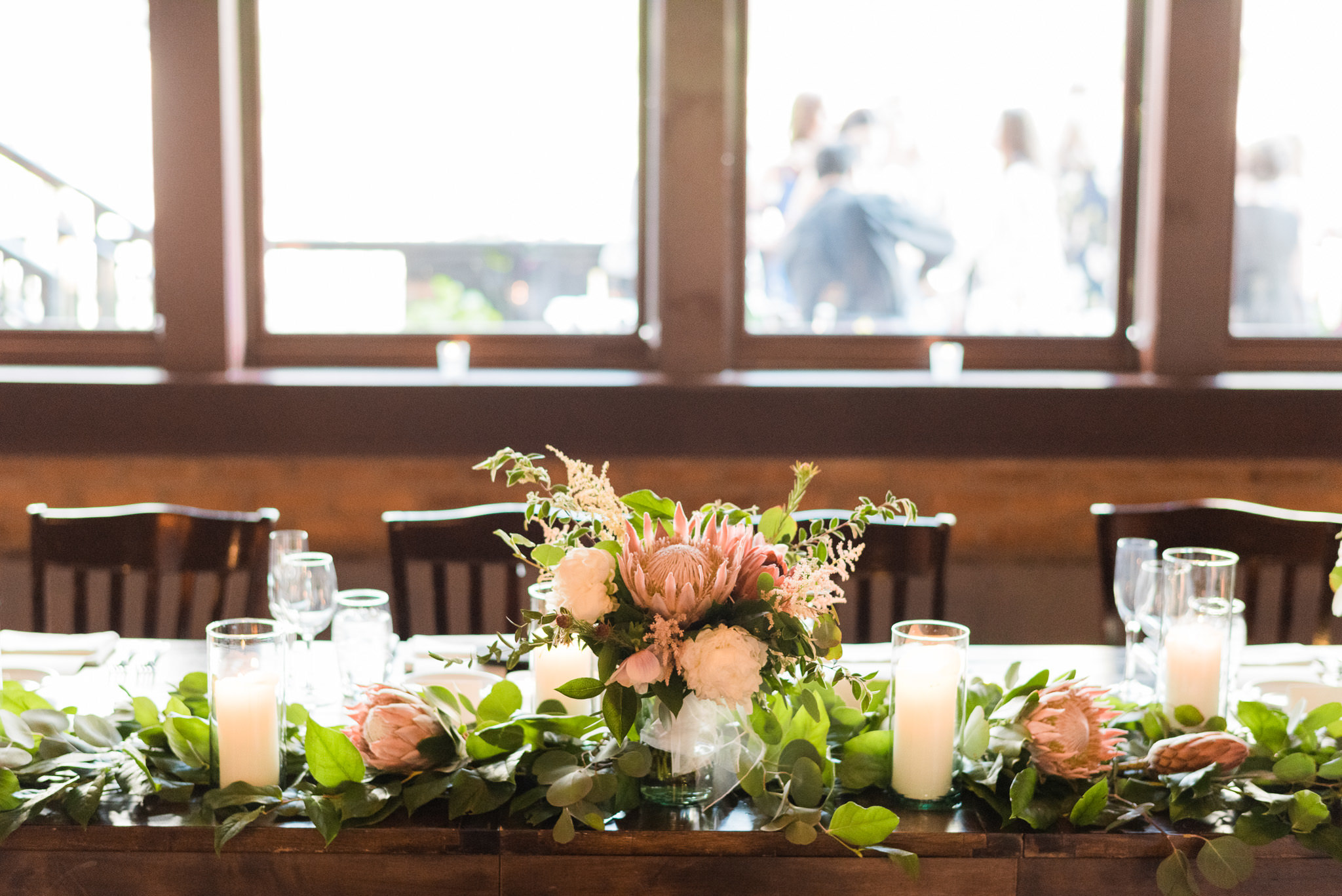 Head table for spring wedding reception at River Roast Chicago, with garlands of eucalpytus and blush protea, astilbe, and peonies. 