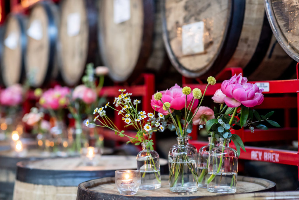 Revolution Brewing Chicago spring wedding with small gathered arrangements of magenta peonies and billy balls in glass vases. 