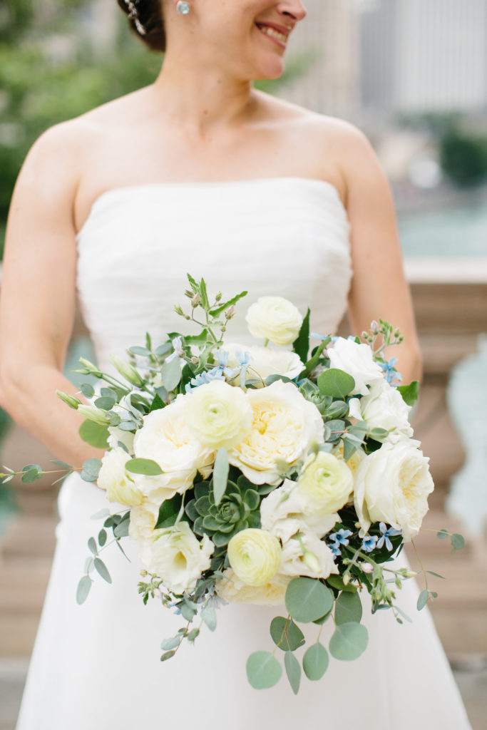 Summer bride with white and blue bouquet of ivory garden roses, ranunculus, succulents, tweedia, and eucalyptus. 