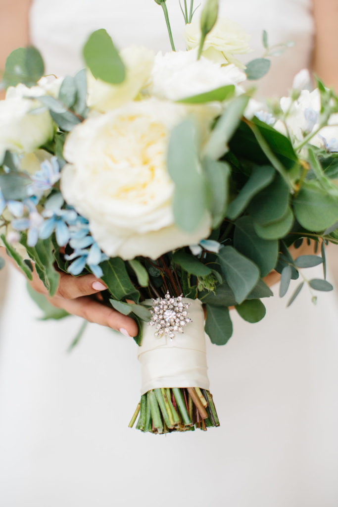 Detail of bridal bouquet with heirloom pin for an Adler Planetarium summer wedding in soft colors of ivory and blue. 