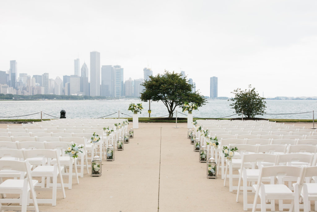 July outdoor summer wedding at Adler Planetarium with chair swags and silver lanterns lining the aisle made from blue hydrangea and ivory garden roses.