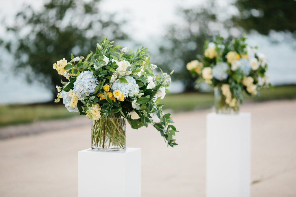 Altar arrangements for outdoor July wedding at Adler Planetarium with blue hydrangea, yellow spray roses, buttercream stock, and ivory garden roses.