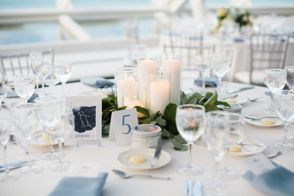 Pillar candles and eucalyptus centerpiece at Adler Planetarium reception for a summer celestial wedding in pale blue, pale yellow, and white. 