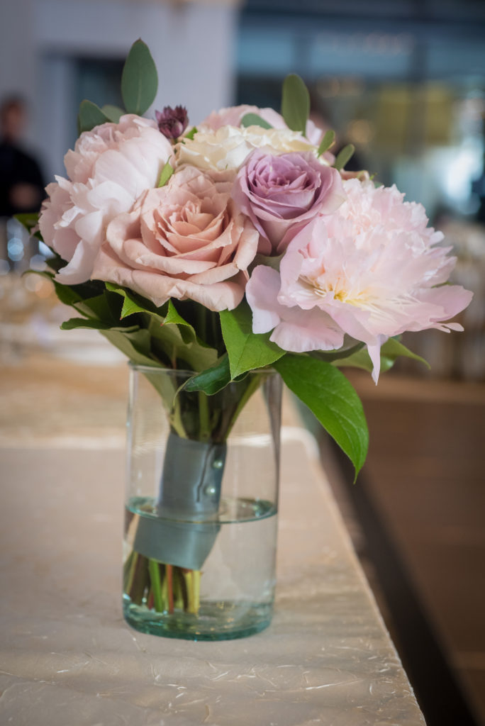 Bridesmaid bouquet of pale pink peonies and mauve, blush, and ivory garden roses on head table for the spring wedding reception.
