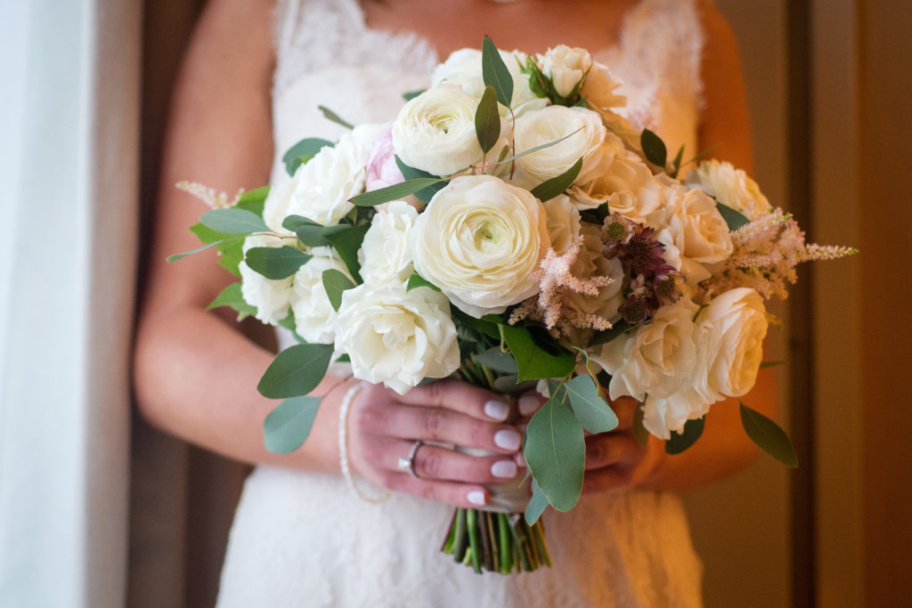 A soft-hued bridal bouquet with ivory ranunculus, garden roses, astilbe, lisianthus, and peonies for a spring wedding.