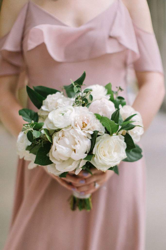 Bridesmaid bouquet close-up with blush peonies, ivory ranunculus, garden roses, and majolica roses for summer outdoor wedding with dusty rose bridesmaid dress
