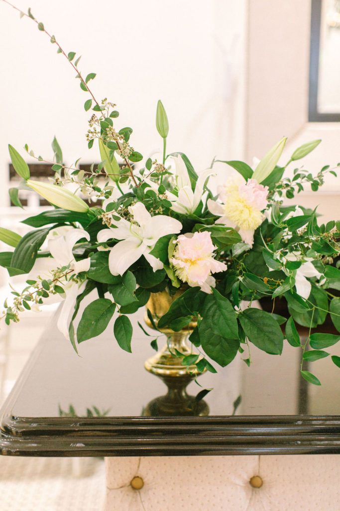 Golden urn vase with full arrangement of pale blush and cream peonies, white ivories, flowering branches, and foliage for a romantic summer wedding and outdoor reception in Chicago.